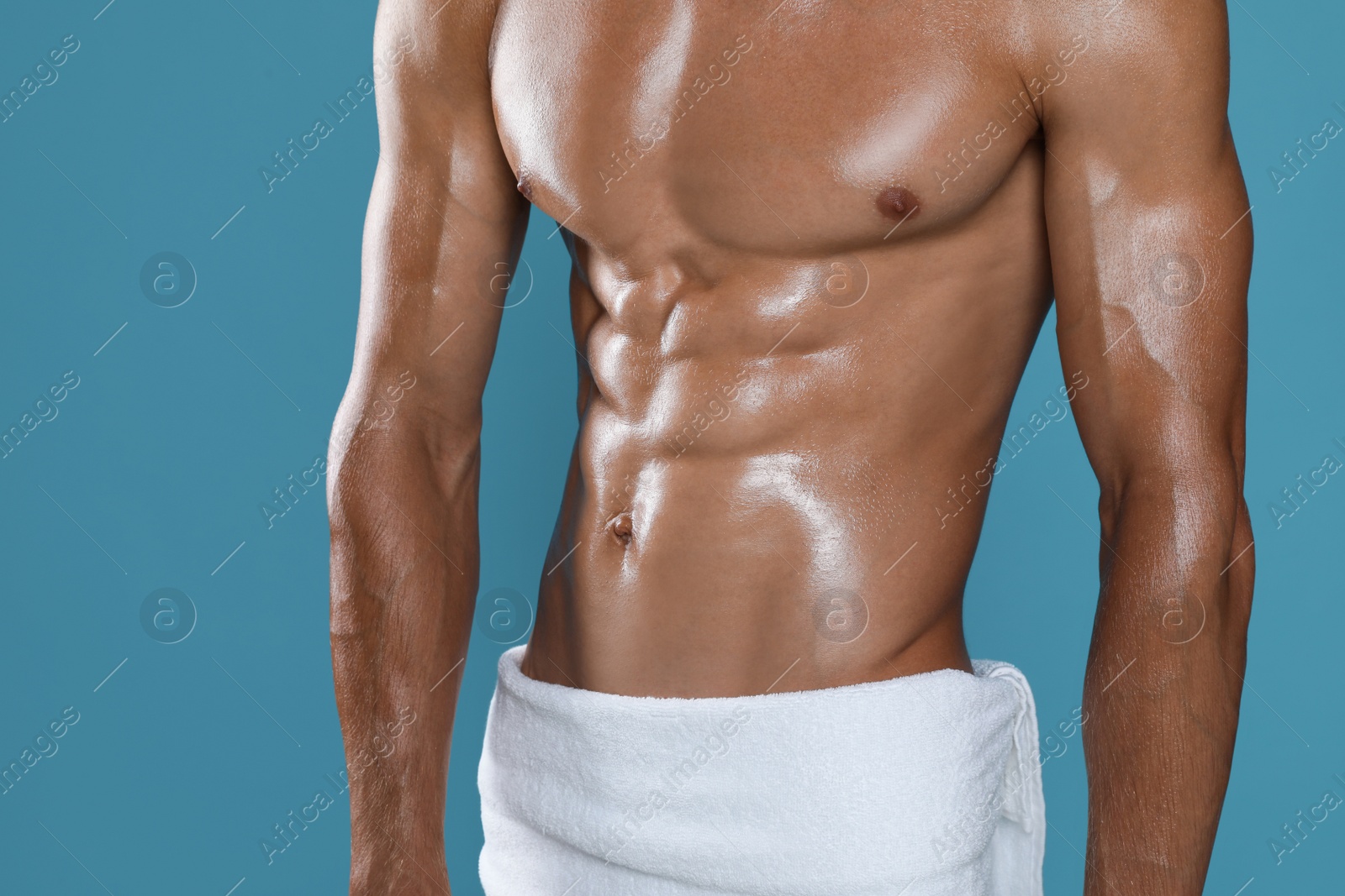 Photo of Shirtless man with slim body and towel wrapped around his hips on light blue background, closeup