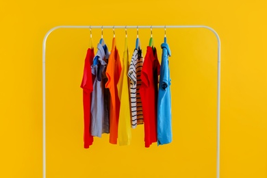 Photo of Rack with stylish children clothes on yellow background