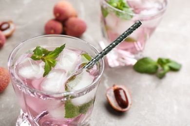 Lychee cocktail with mint and ice on grey table, closeup Photo of Lychee cocktail with mint and ice on grey table, closeup