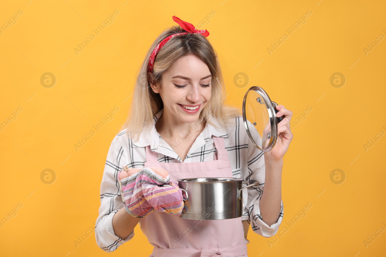 Young housewife with pot on yellow background Photo of Young housewife with pot on yellow background