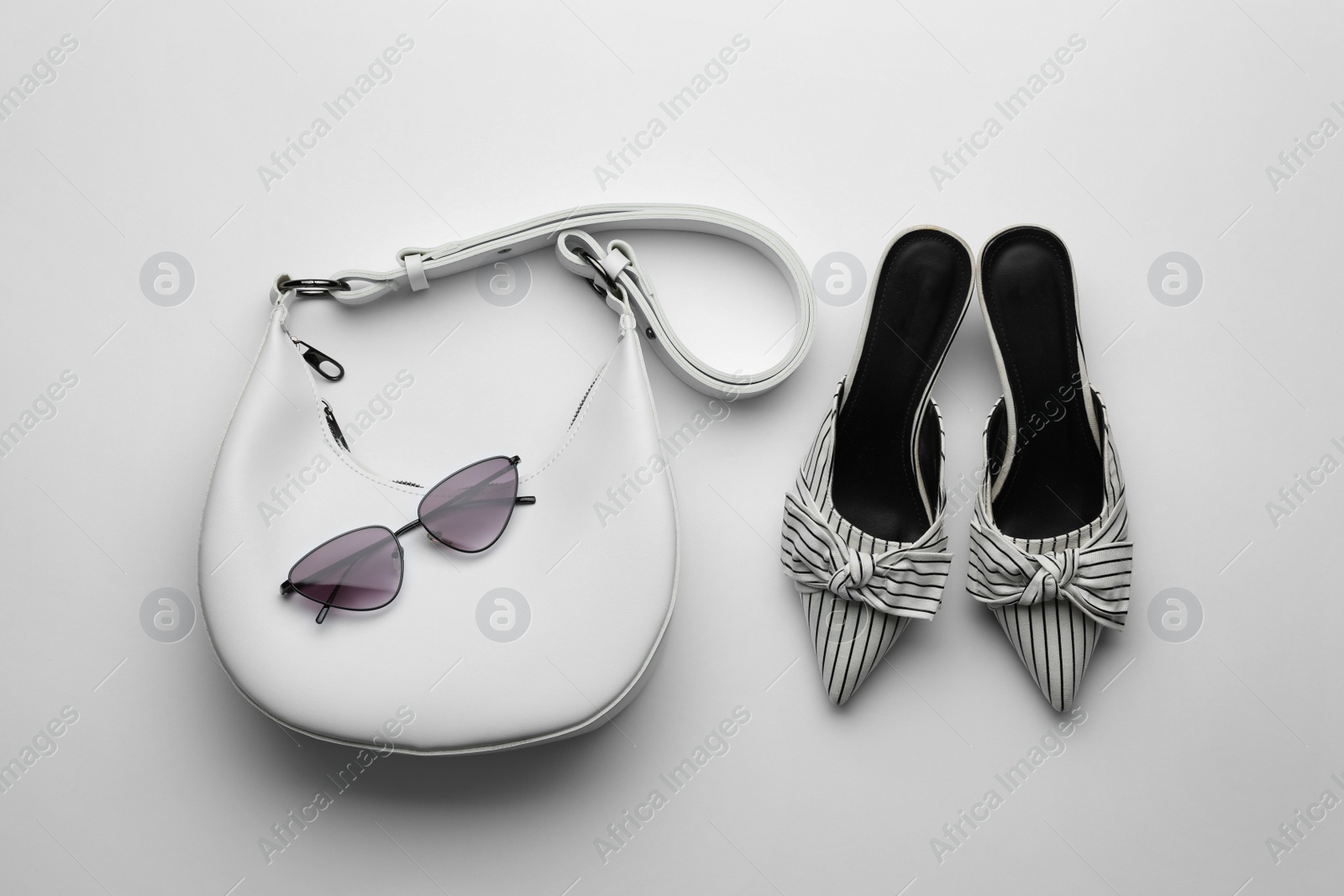 Stylish woman's bag, sunglasses and shoes on light background, flat lay Photo of Stylish woman's bag, sunglasses and shoes on light background, flat lay