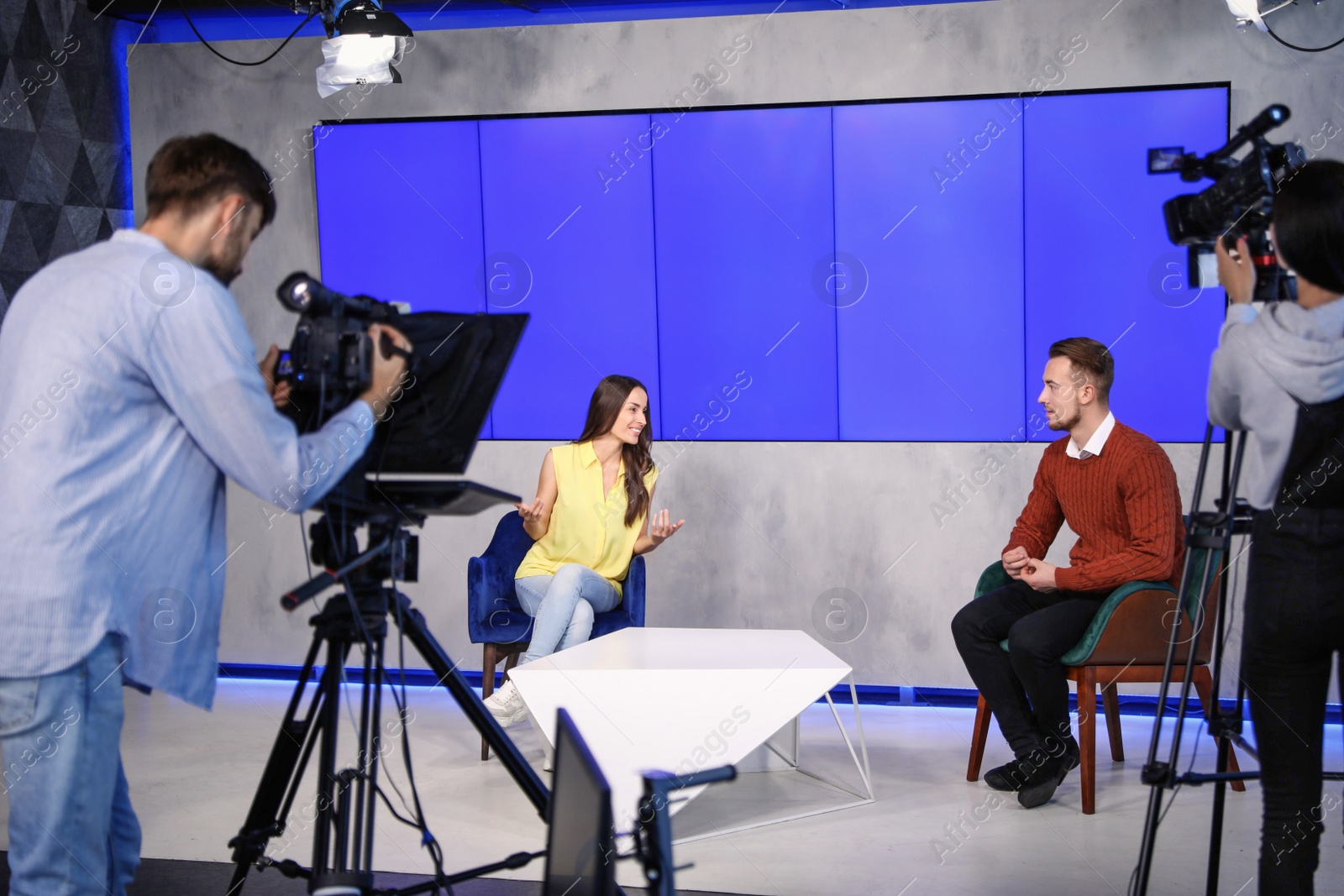 Presenters and video camera operator working in studio. News broadcasting Photo of Presenters and video camera operator working in studio. News broadcasting