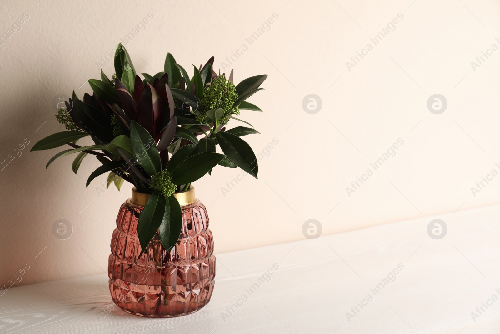 Vase with beautiful bouquet on white wooden table near beige wall. Space for text Photo of Vase with beautiful bouquet on white wooden table near beige wall. Space for text