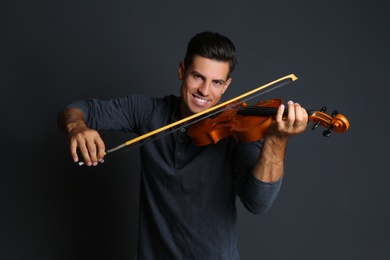 Happy man playing violin on black background Photo of Happy man playing violin on black background