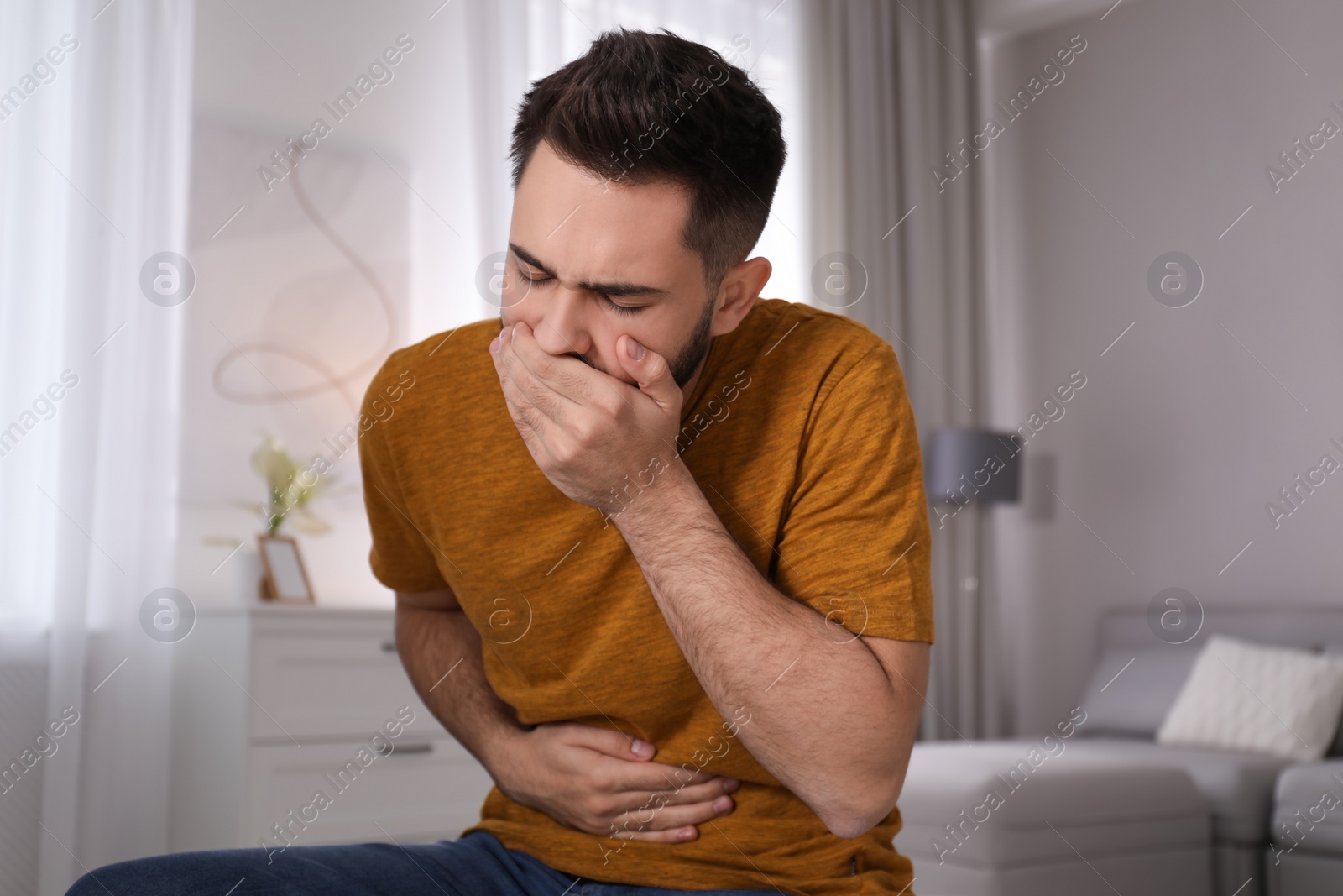 Young man suffering from nausea at home. Food poisoning Photo of Young man suffering from nausea at home. Food poisoning