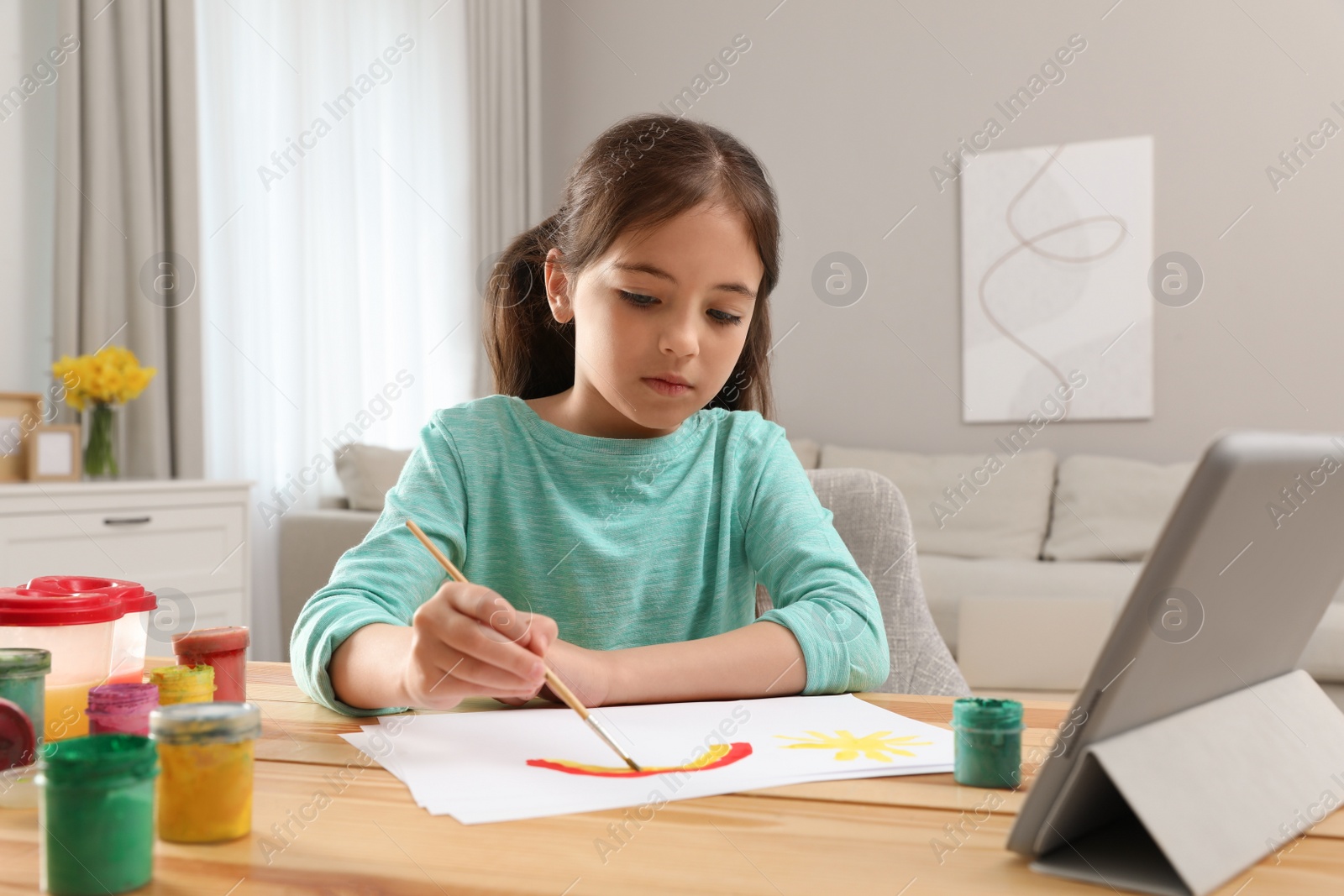 Little girl drawing on paper with paints at online lesson indoors. Distance learning Photo of Little girl drawing on paper with paints at online lesson indoors. Distance learning