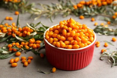 Fresh ripe sea buckthorn in bowl on grey table Photo of Fresh ripe sea buckthorn in bowl on grey table