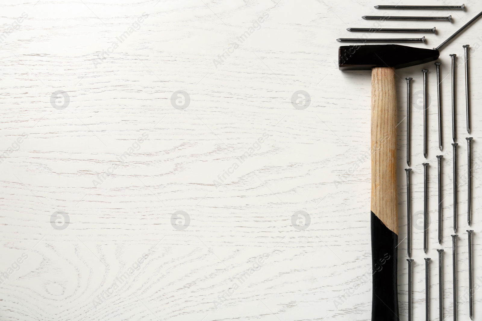 Hammer and metal nails on white wooden table, flat lay. Space for text Photo of Hammer and metal nails on white wooden table, flat lay. Space for text