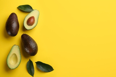 Whole and cut ripe avocadoes with green leaves on yellow background, flat lay. Space for text Photo of Whole and cut ripe avocadoes with green leaves on yellow background, flat lay. Space for text