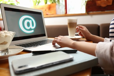 Woman sending email via laptop in cafe, closeup Image of Woman sending email via laptop in cafe, closeup