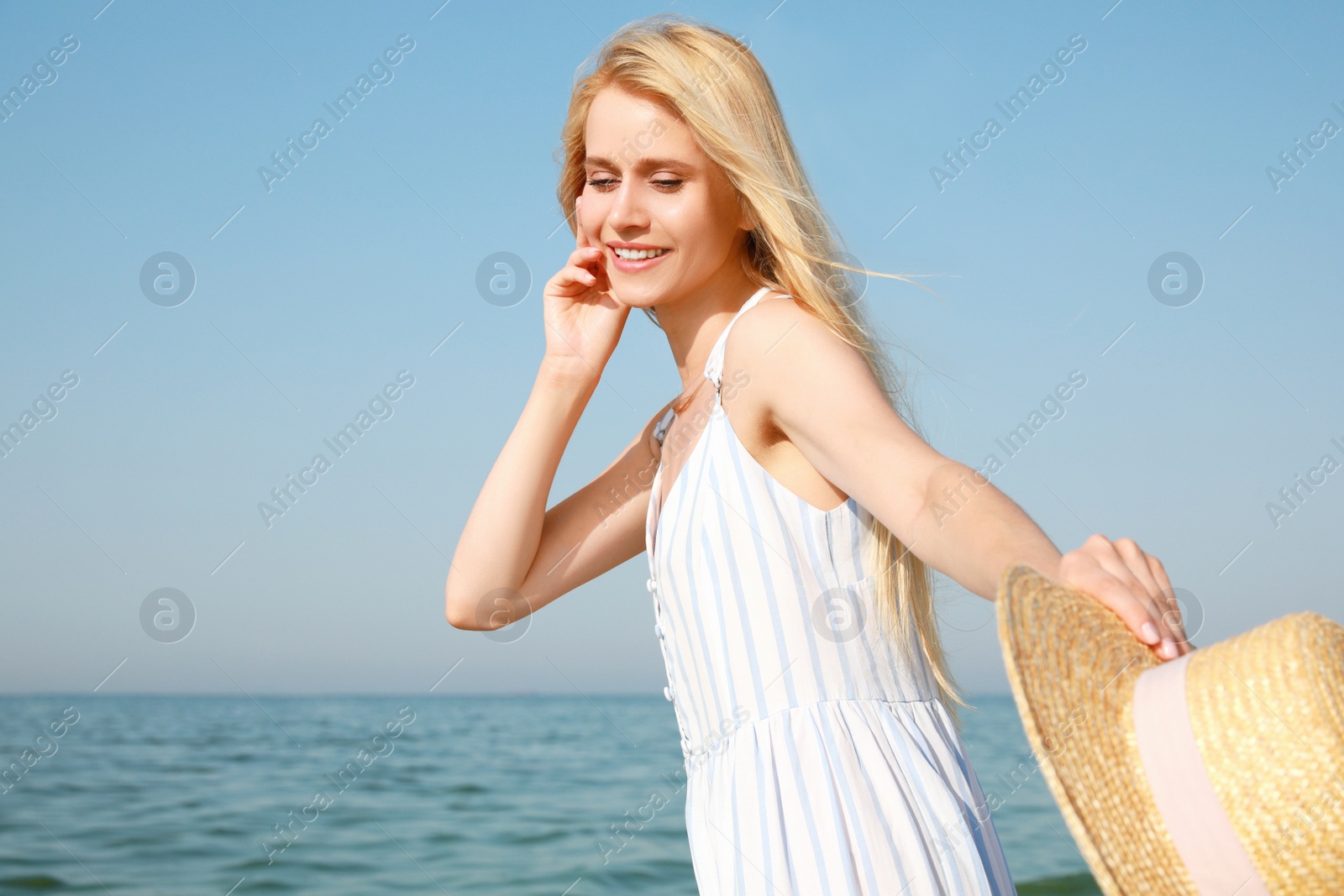 Beautiful young woman with straw hat near sea on sunny day in summer Photo of Beautiful young woman with straw hat near sea on sunny day in summer