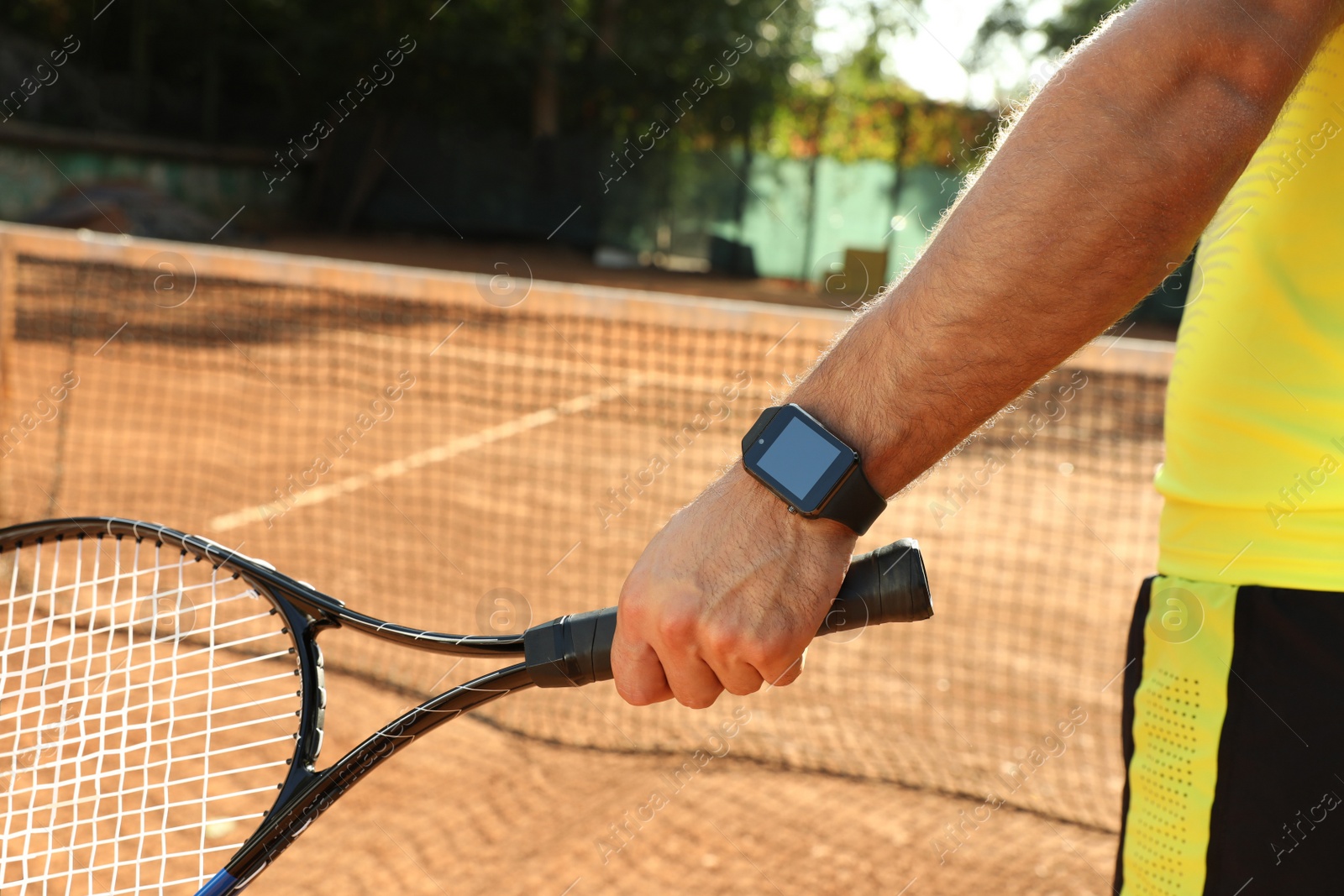 Man wearing modern smart watch during training on tennis court, closeup Photo of Man wearing modern smart watch during training on tennis court, closeup