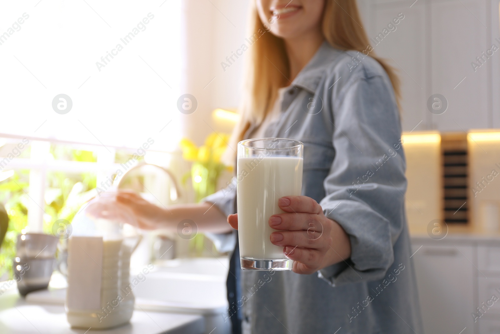 Young woman with gallon bottle of milk and glass at white countertop in kitchen, closeup Photo of Young woman with gallon bottle of milk and glass at white countertop in kitchen, closeup