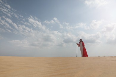 Photo of Jesus Christ walking with stick in desert. Space for text