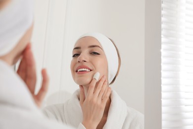 Woman using silkworm cocoon in skin care routine near mirror at home Photo of Woman using silkworm cocoon in skin care routine near mirror at home