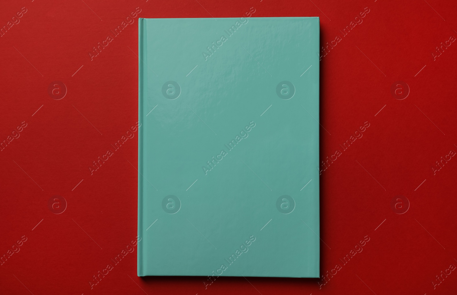 New stylish planner with hard cover on red background, top view Photo of New stylish planner with hard cover on red background, top view