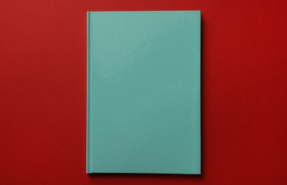 New stylish planner with hard cover on red background, top view Photo of New stylish planner with hard cover on red background, top view