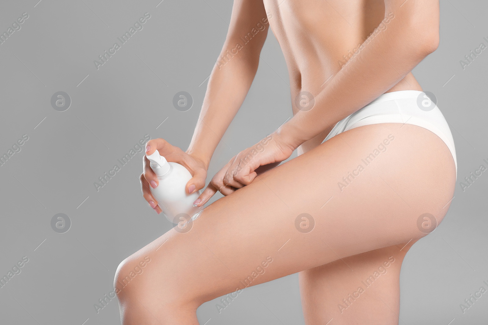 Young woman with bottle of body cream on color background Photo of Young woman with bottle of body cream on color background