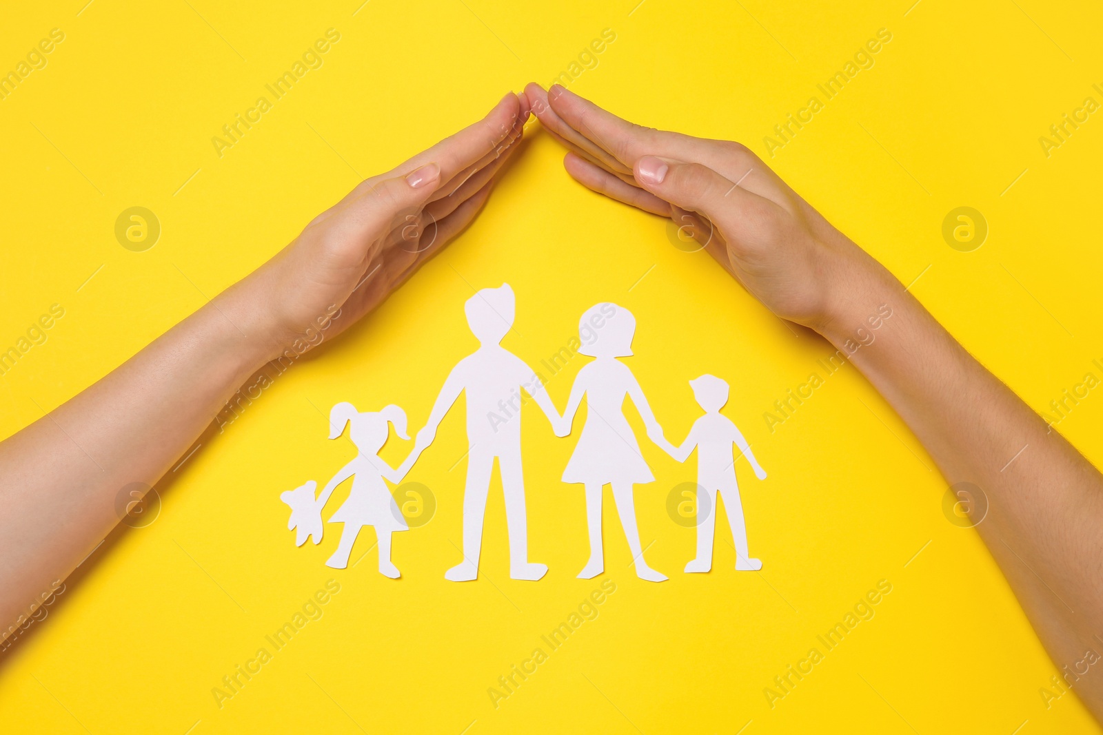 Woman and man covering paper family figures with hands on yellow background, top view Photo of Woman and man covering paper family figures with hands on yellow background, top view