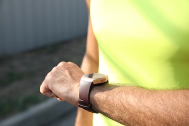 Man checking fitness tracker after training outdoors, closeup Photo of Man checking fitness tracker after training outdoors, closeup