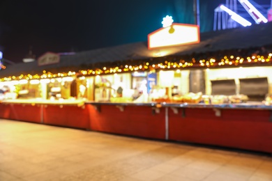 Blurred view of Christmas fair stalls outdoors at night Photo of Blurred view of Christmas fair stalls outdoors at night
