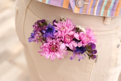 Woman wearing jeans with flowers in pocket, closeup Photo of Woman wearing jeans with flowers in pocket, closeup