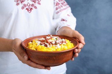 Woman holding bowl of banosh with brynza and pork cracklings on blue background, closeup. Traditional Ukrainian dish Photo of Woman holding bowl of banosh with brynza and pork cracklings on blue background, closeup. Traditional Ukrainian dish