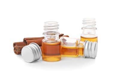 Bottles of cinnamon oil and sticks on white background Photo of Bottles of cinnamon oil and sticks on white background