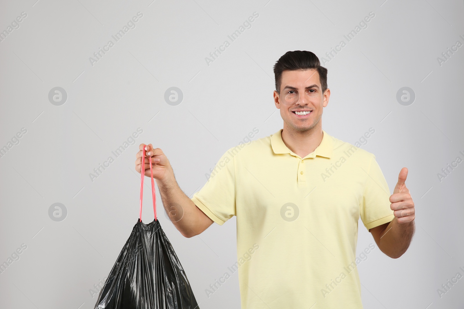 Man holding full garbage bag on light background Photo of Man holding full garbage bag on light background
