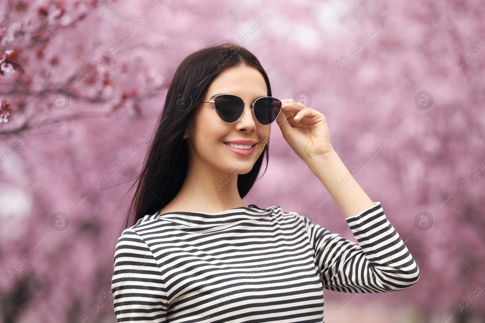 Pretty young woman in park with blooming trees. Spring look Photo of Pretty young woman in park with blooming trees. Spring look
