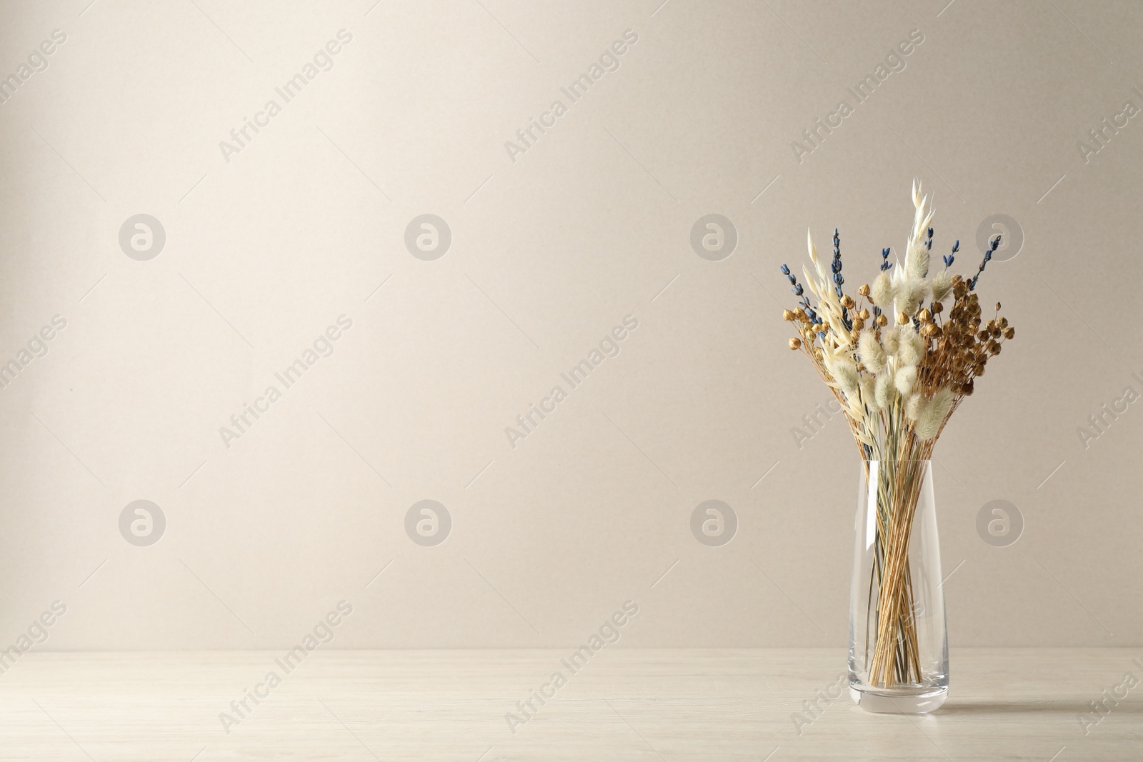 Dried flowers in vase on table against light background. Space for text Photo of Dried flowers in vase on table against light background. Space for text