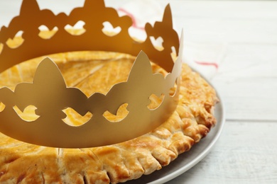 Traditional galette des Rois with paper crown on white wooden table, closeup Photo of Traditional galette des Rois with paper crown on white wooden table, closeup