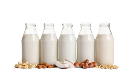 Vegan milk and different nuts on white background Photo of Vegan milk and different nuts on white background