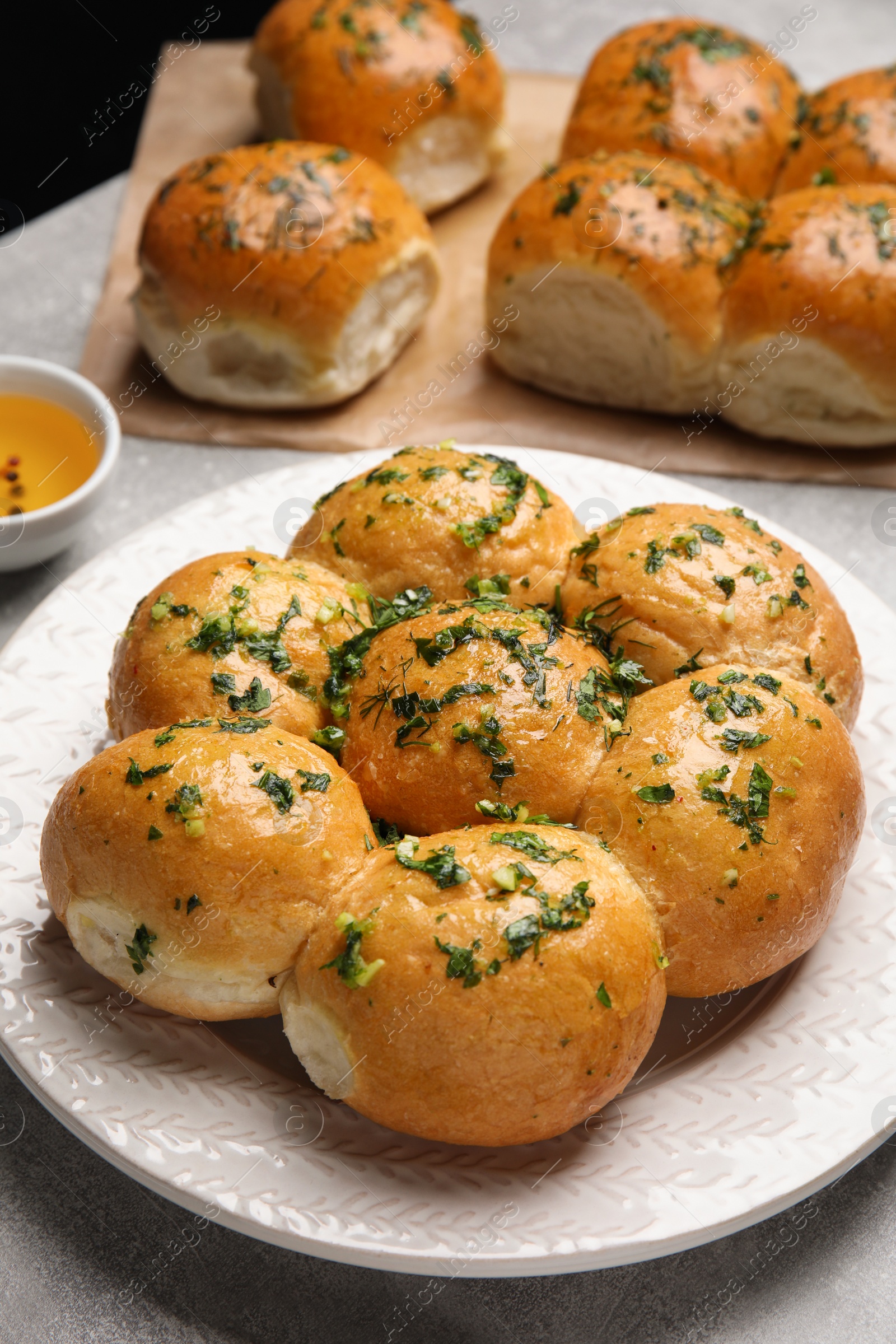 Traditional pampushka buns with garlic and herbs on grey table Photo of Traditional pampushka buns with garlic and herbs on grey table