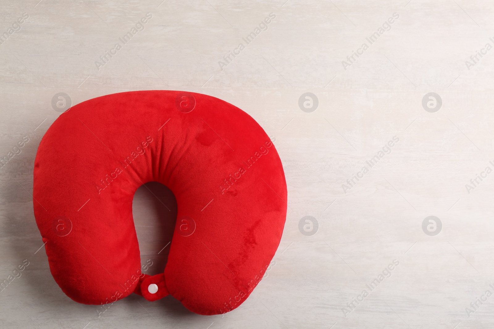 Red travel pillow on light background, top view. Space for text Image of Red travel pillow on light background, top view. Space for text