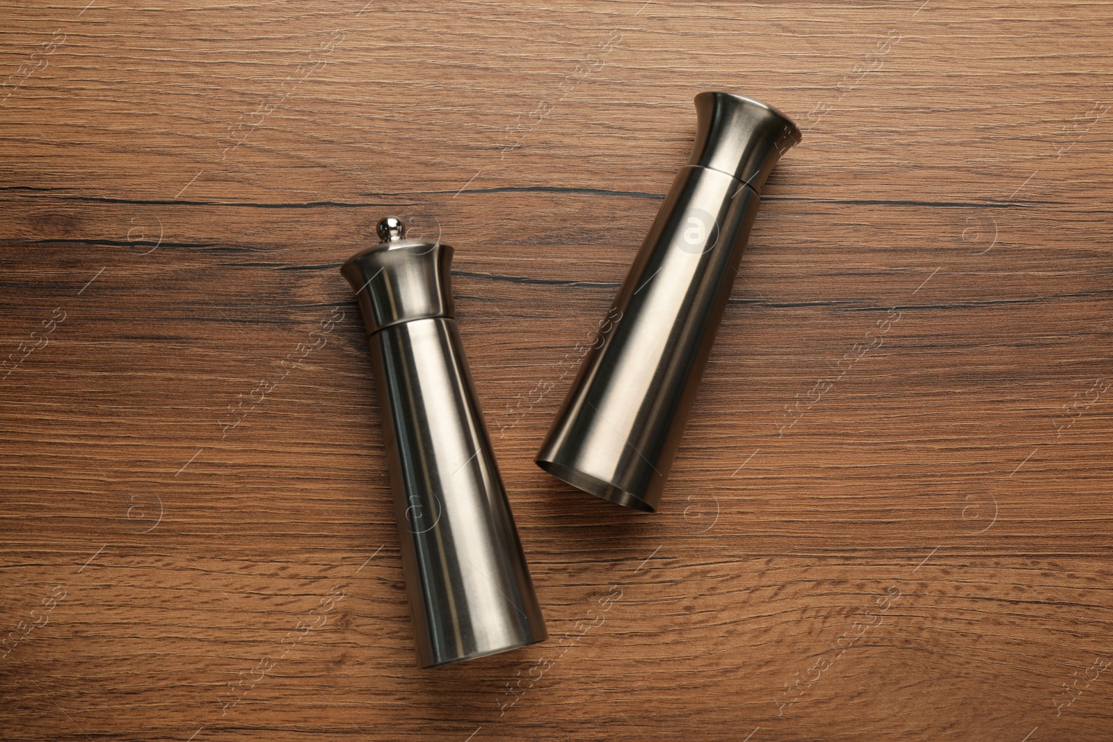 Stainless salt and pepper shakers on wooden table, flat lay Photo of Stainless salt and pepper shakers on wooden table, flat lay