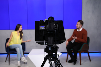 Photo of Presenters working in studio, focus on video camera