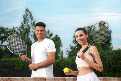 Couple with tennis rackets and ball at court Photo of Couple with tennis rackets and ball at court