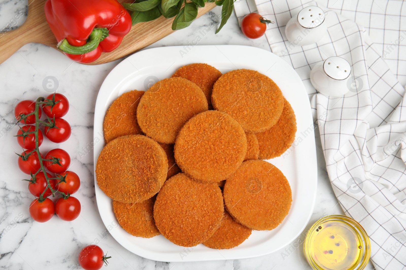 Delicious fried breaded cutlets, spices and vegetables on white marble table, flat lay Photo of Delicious fried breaded cutlets, spices and vegetables on white marble table, flat lay