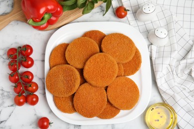 Delicious fried breaded cutlets, spices and vegetables on white marble table, flat lay Photo of Delicious fried breaded cutlets, spices and vegetables on white marble table, flat lay
