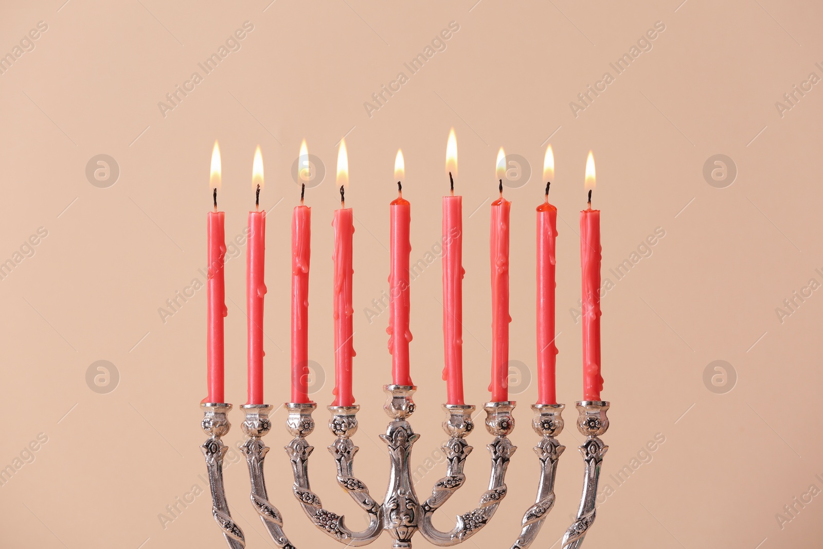 Silver menorah with burning candles on beige background. Hanukkah celebration Photo of Silver menorah with burning candles on beige background. Hanukkah celebration