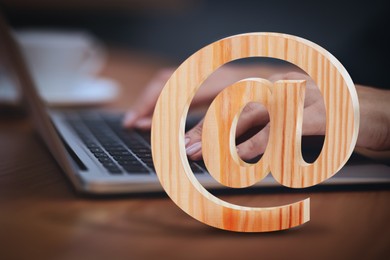 At sign illustration and woman sending email via laptop at table, closeup Image of At sign illustration and woman sending email via laptop at table, closeup