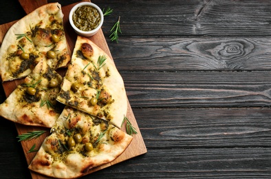 Delicious focaccia bread with green olives on black wooden table, top view. Space for text Photo of Delicious focaccia bread with green olives on black wooden table, top view. Space for text