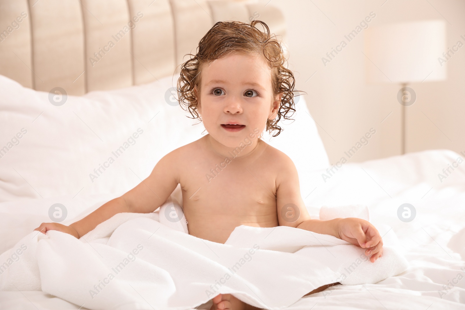 Cute little baby with soft towel on bed after bath Photo of Cute little baby with soft towel on bed after bath
