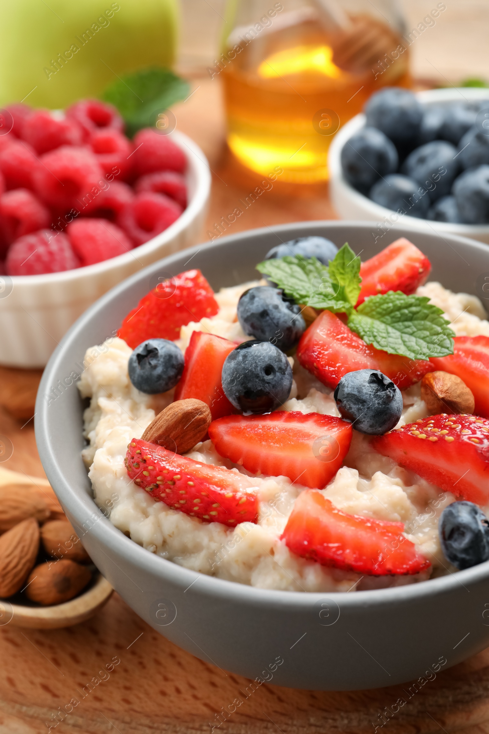 Tasty oatmeal porridge with berries and almond nuts in bowl served on wooden board Photo of Tasty oatmeal porridge with berries and almond nuts in bowl served on wooden board