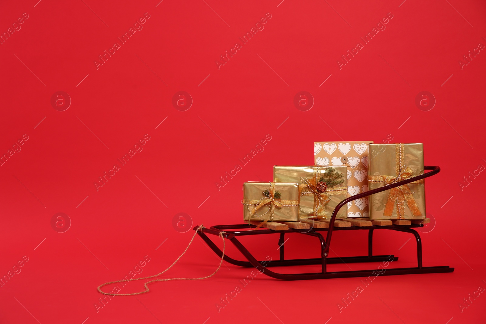 Sleigh with gift boxes on red background. Space for text Photo of Sleigh with gift boxes on red background. Space for text