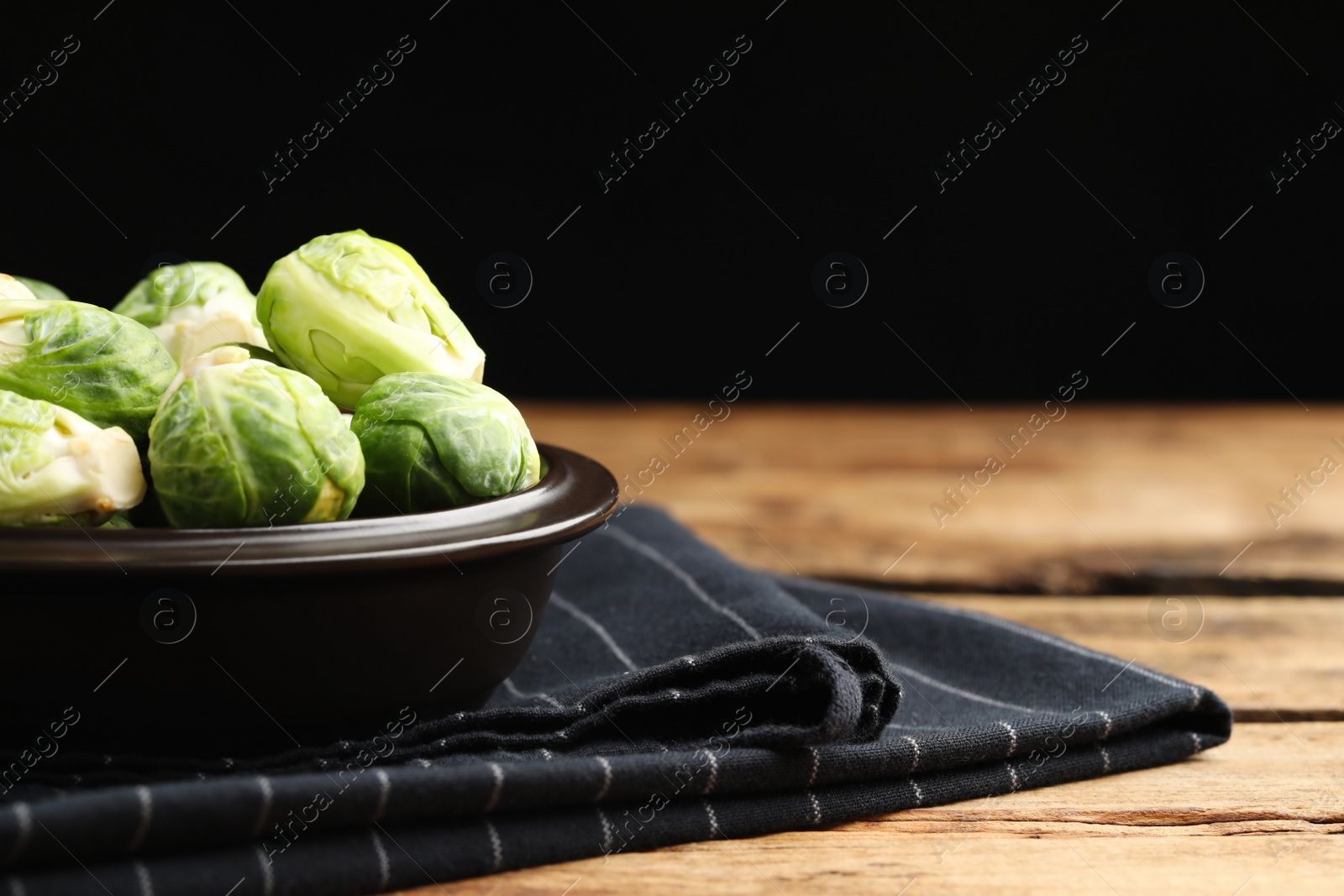 Bowl with fresh Brussels sprouts on wooden table, closeup. Space for text Photo of Bowl with fresh Brussels sprouts on wooden table, closeup. Space for text