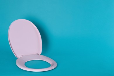 New pink plastic toilet seat on light blue background, space for text Photo of New pink plastic toilet seat on light blue background, space for text