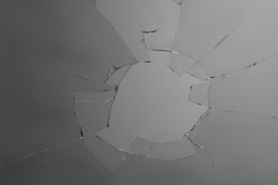 Closeup view of broken glass with cracks on grey background Photo of Closeup view of broken glass with cracks on grey background