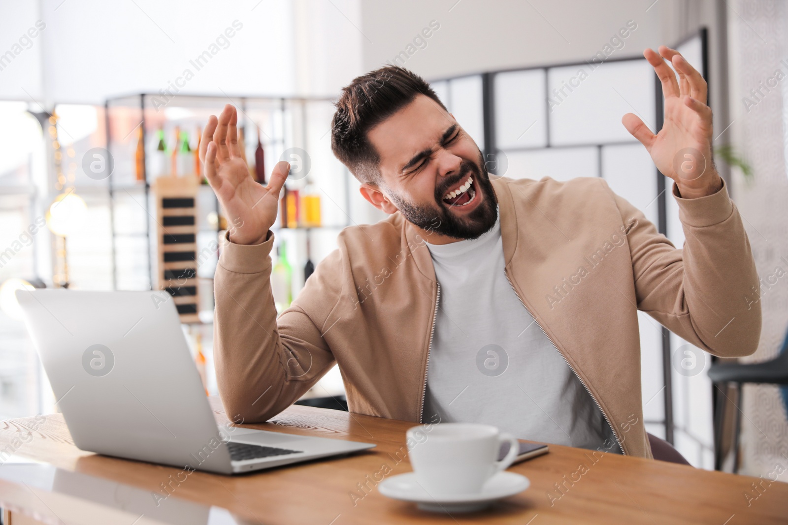 Emotional young man working on laptop in office. Online hate concept Photo of Emotional young man working on laptop in office. Online hate concept